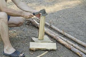 um homem corta madeira com um machado para aquecimento. foto