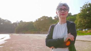 mulher asiática idosa olhando para o mar em uma praia tranquila. foto