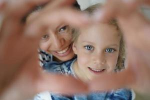 filha adotiva, mãe faz gesto de coração, símbolo de apoio ao cuidado do amor infantil. maternidade, adoção foto