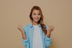 jovem mulher segurando as mãos em punhos no fundo bege foto