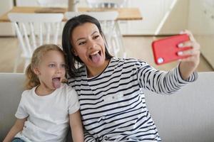 afetuosa mãe e filho estão tomando selfie. jovem mãe europeia faz foto com a filha.