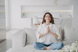 serena jovem latina praticando exercícios de ioga e postura, lótus asana em casa. foto