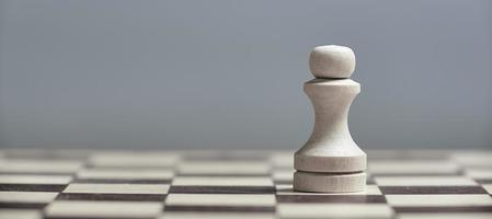 um peão branco close-up em um tabuleiro de xadrez em um fundo cinza. fundo em desfoque. foto