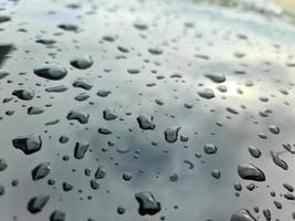 chuva cai em uma superfície de carro metálico preto em uma visão de closeup. foto
