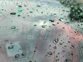 chuva cai em uma superfície de carro metálico preto em uma visão de closeup. foto