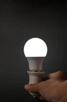 lâmpada led móvel que ilumina uma luz branca em um fundo preto no escuro foto