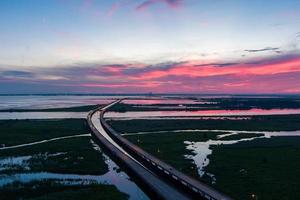 vista aérea da ponte móvel bay e jubilee parkway ao pôr do sol na costa do golfo do alabama foto