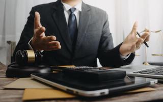 conceito de justiça e direito. juiz masculino em um tribunal com o martelo, trabalhando com, computador e teclado de encaixe, óculos, na mesa na luz da manhã foto