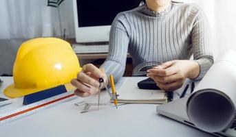 dois colegas discutindo dados de trabalho e tablet, laptop com projeto arquitetônico no canteiro de obras na mesa no escritório foto