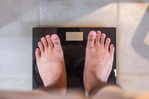 homem ficar na escala de peso digital. dieta, perda de peso, excesso de peso, obesidade e conceito de saúde foto