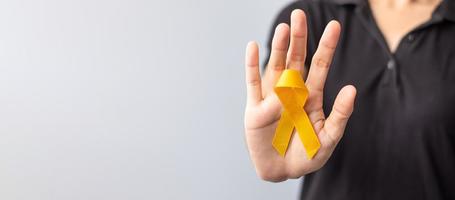 dia de prevenção do suicídio, infância, sarcoma, mês de conscientização do câncer de osso e bexiga, fita amarela para apoiar a vida e a doença das pessoas. saúde infantil e conceito de dia mundial do câncer foto