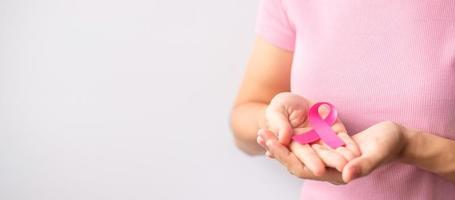 mês de conscientização do câncer de mama de outubro rosa, a mão da mulher segura a fita rosa e usa camisa para apoiar a vida e a doença das pessoas. mês nacional de sobreviventes de câncer, mãe e conceito de dia mundial do câncer foto