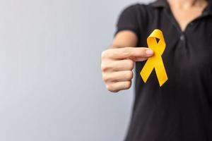 dia de prevenção do suicídio, infância, sarcoma, mês de conscientização do câncer de osso e bexiga, fita amarela para apoiar a vida e a doença das pessoas. saúde infantil e conceito de dia mundial do câncer foto