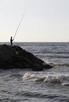 homem em cuba pescando na costa foto