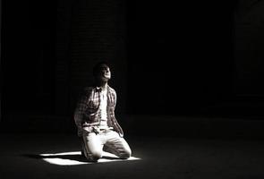 jovem ajoelhado em um feixe de luz em uma mesquita em Teerã, Irã foto
