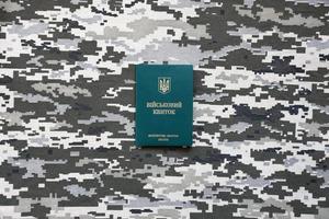 id militar ucraniano em tecido com textura de camuflagem pixelizada. pano com padrão de camuflagem em formas de pixel cinza, marrom e verde com símbolo pessoal do exército ucraniano foto