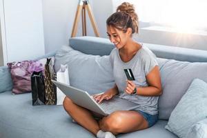 imagem mostrando uma linda mulher fazendo compras on-line com cartão de crédito. mulher segurando o cartão de crédito e usando o laptop. conceito de compras online foto