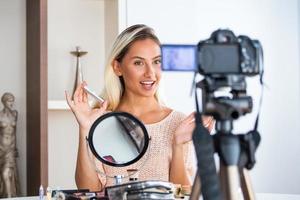 jovem falando sobre cosméticos segurando uma paleta de maquiagem durante a gravação de seu vídeo. mulher fazendo um vídeo para seu blog sobre cosméticos. foto