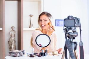 jovem linda loira vlogger de beleza profissional ou blogger gravando tutorial de maquiagem para compartilhar nas mídias sociais foto