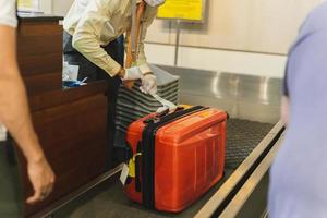 funcionário coloca etiqueta na bagagem dos passageiros no aeroporto. foto
