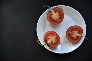 fruta de tomate linda madura em uma vista superior de chapa branca. deliciosos tomates ainda vida. foto