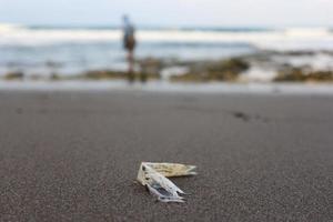 lixo derramado na praia da cidade grande. esvaziar o plástico sujo usado. costa arenosa do mar sujo do oceano híndio. poluição ambiental. problema ecológico. bokeh movendo ondas no fundo foto