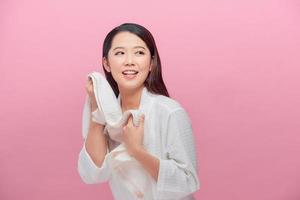 mulher bonita alegre com pele saudável secando o rosto com toalha de algodão macio branco após higiene matinal na frente da câmera foto