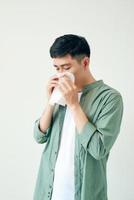 jovem asiático espirrando depois de ter alergia ou vírus da gripe e usando papel de seda para deslizar no nariz na clínica médica depois de ter doença de coronavírus por conceito de estilo de vida pouco saudável foto