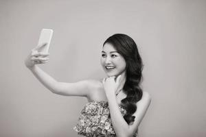 jovem mulher tirando foto de selfie no smartphone olhando câmera rindo feliz. foto preto e branco