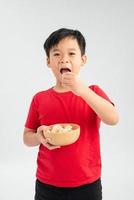 menino comendo um bebê de geléia de uma tigela de doces de pirulitos coloridos misturados. foto