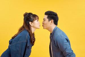 perfis de namorada e namorado dando um ao outro um beijo de ar sobre amarelo foto