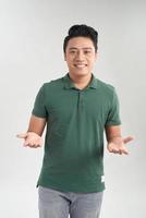 lindo homem casual com camiseta verde falando com duas mãos abertas feliz sobre fundo branco foto