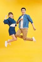 vista de tamanho de corpo inteiro de um belo e alegre casal alegre e atraente pulando no ar isolado sobre fundo amarelo foto