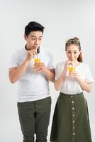 casal jovem feliz com copos de suco de laranja isolado em um fundo branco. foto