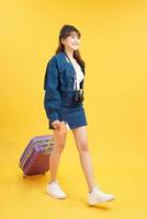 jovem turista em roupas casuais de verão, com mala roxa, passaporte, bilhetes isolados em fundo amarelo foto