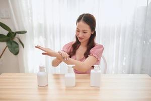 linda mulher asiática usando desinfetante para as mãos em casa. foto