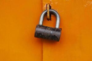 trava na porta. fechadura de aço no portão laranja. porta fechada. foto