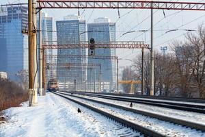 rodovia ferroviária multilinha com um trem elétrico em movimento no contexto de uma paisagem urbana de inverno. foto