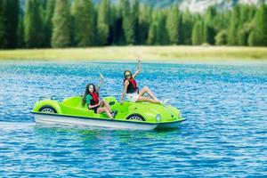 meninas em um pedalinho verde em um lago de montanha foto