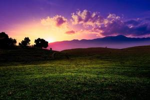 dramática paisagem por do sol com prado e montanha. foto