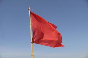 bandeira vermelha balançando ao vento em um fundo de céu azul foto