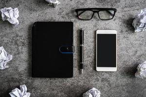 bolas de papel amassado com notebook e smartphone no escritório de mesa, conceito de problemas de criatividade foto