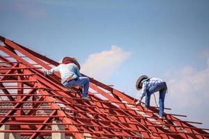 trabalhadores de solda instalando estrutura de armação de aço do telhado da casa no canteiro de obras foto