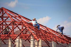 trabalhadores de solda instalando estrutura de armação de aço do telhado da casa no canteiro de obras foto