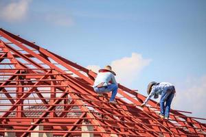 trabalhadores de solda instalando estrutura de armação de aço do telhado da casa no canteiro de obras foto