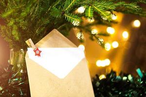 envelope com folha de papel-carta para papai noel, copie o espaço em um fundo de natal de luzes de desfocagem em bokeh, guirlandas, ramos de abeto. prendedor de roupa-estrela. ano novo, lista de desejos, sonho, presentes foto