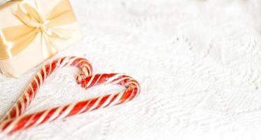 pirulito de natal listrado papai noel em forma de coração em um cobertor de malha branco. um símbolo de amor, um presente para um ente querido, um doce. ano Novo. espaço para texto foto