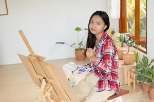 jovem pintando em papel em casa, moldura de madeira, hobby e estudo de arte em casa. foto