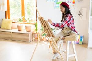 jovem pintando em papel em casa, moldura de madeira, hobby e estudo de arte em casa. foto