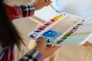 jovem pintando em papel em casa, moldura de madeira, hobby e estudo de arte em casa. foto